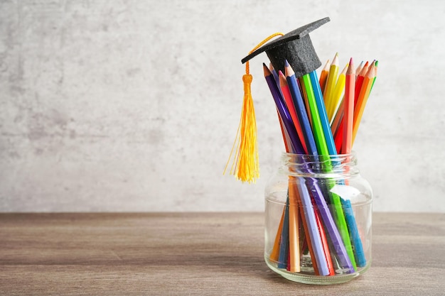 Cappello di laurea con matite colorate sul libro con spazio di copia per l'apprendimento del concetto di istruzione universitaria