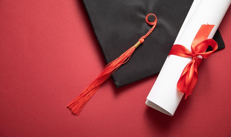 Cappello di laurea e diploma sullo sfondo bordeaux