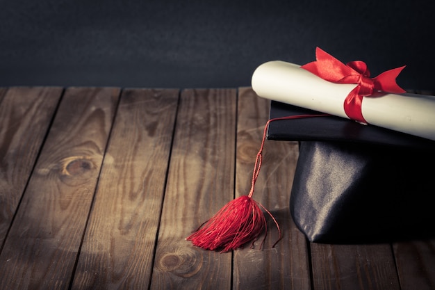 Cappello di laurea e diploma sullo sfondo