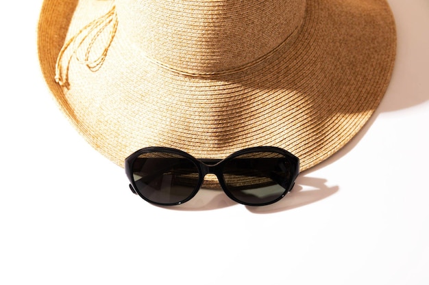 Cappello di paglia da spiaggia con occhiali da sole su bianco