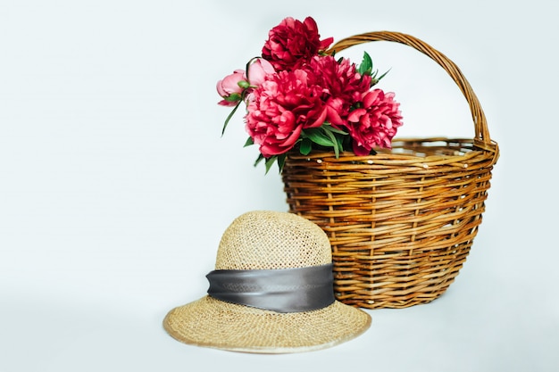 Cappello di paglia e peonie a cesto