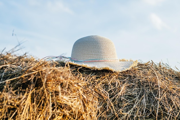 Cappello di panama femminile di vimini che giace in cima al pagliaio Bel cielo blu chiaro Mucchio di erba secca Stile di vita di campagna