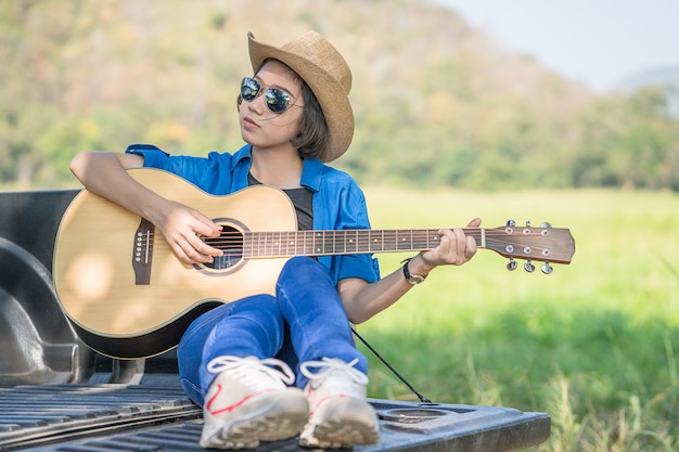 Cappello di usura della donna e suonare la chitarra sul camioncino