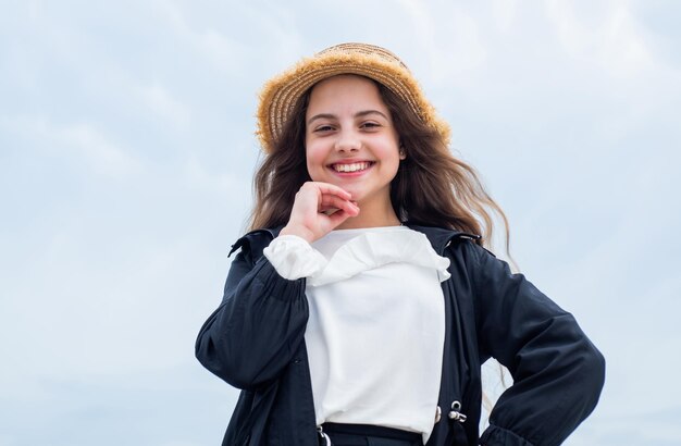 Cappello di usura della ragazza teenager felice all'aperto sull'infanzia del fondo del cielo