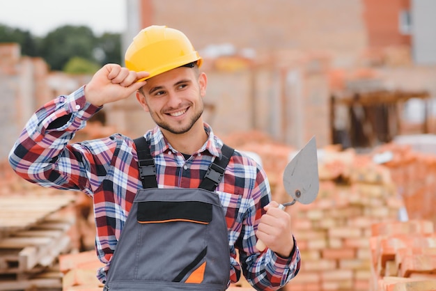 Cappello duro di colore giallo Giovane uomo che lavora in uniforme alla costruzione durante il giorno