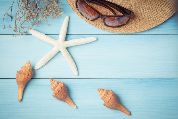 Cappello e coperture sul pavimento di legno del blu, concetto di estate