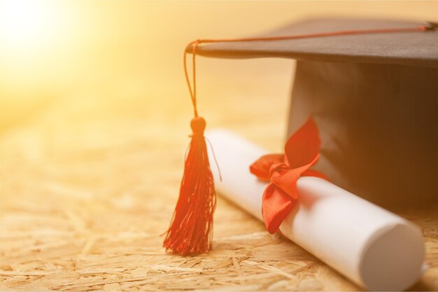 Cappello e diploma di laurea su fondo di legno