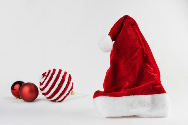 Cappello e palline di Babbo Natale isolati su sfondo bianco. Ornamento di Natale. Messa a fuoco selettiva.