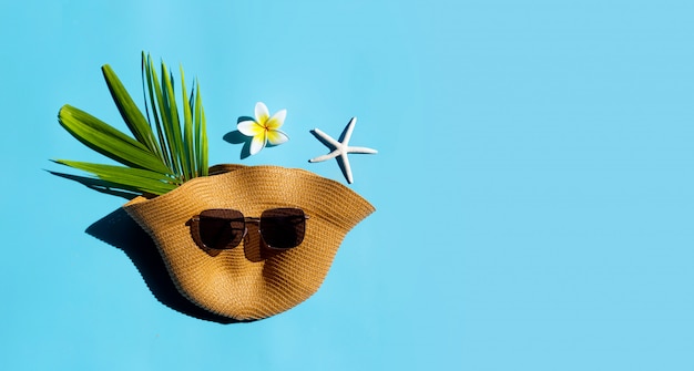 Cappello estivo con occhiali da sole su sfondo blu. Goditi il concetto di vacanza.