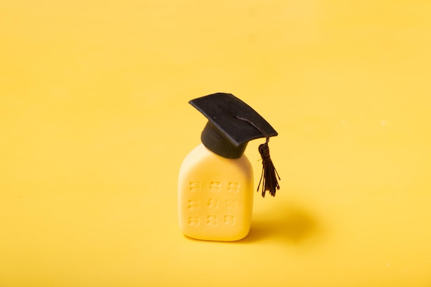 Cappello laureato sull'edificio astratto Concetto di istituto di istruzione Sfondo giallo