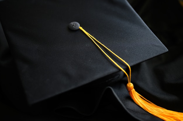 Cappello nero di graduazione di primo piano e nappa gialla posizionati sul pavimento