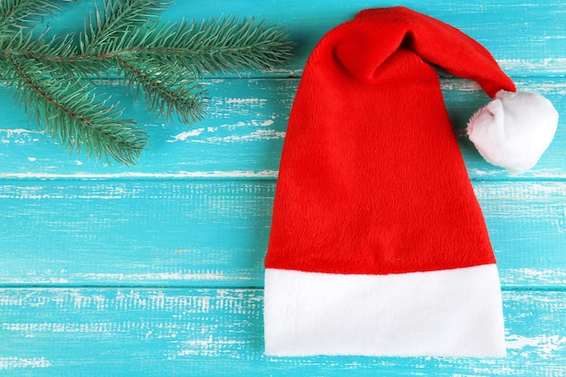 Cappello rosso di Babbo Natale con ramo di abete su fondo in legno colorato
