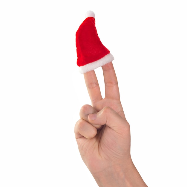 Cappello rosso di Babbo Natale sulle dita della mano che simboleggia il segno della vittoria su uno sfondo bianco