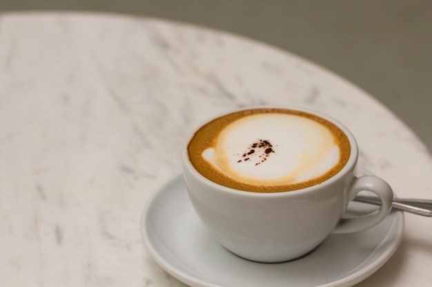 Cappuccino caffè in una tazza bianca caffè sul tavolo