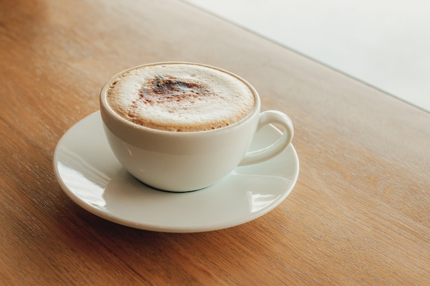 Cappuccino della tazza di caffè sulla barra di legno in caffè.