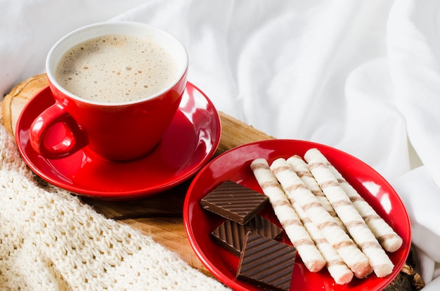 Cappuccino e cioccolato su un letto con plaid.