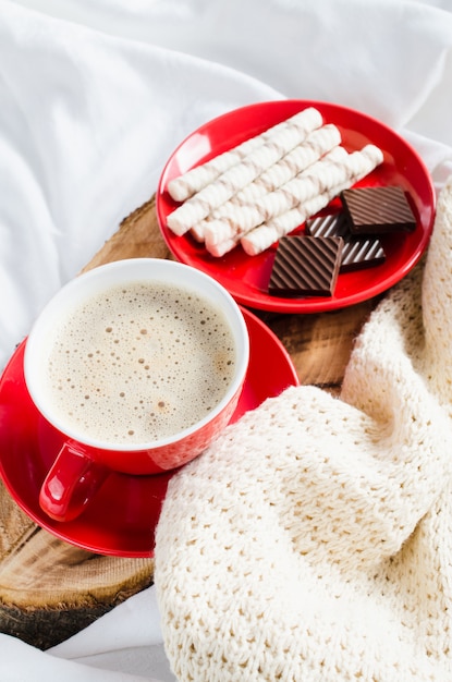 Cappuccino e cioccolato su un letto con plaid.