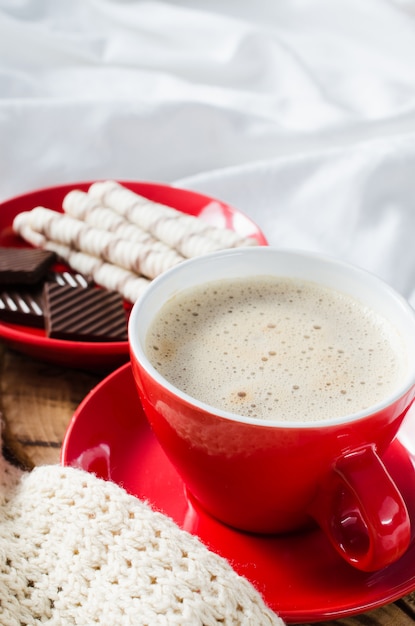 Cappuccino e cioccolato su un letto con plaid.