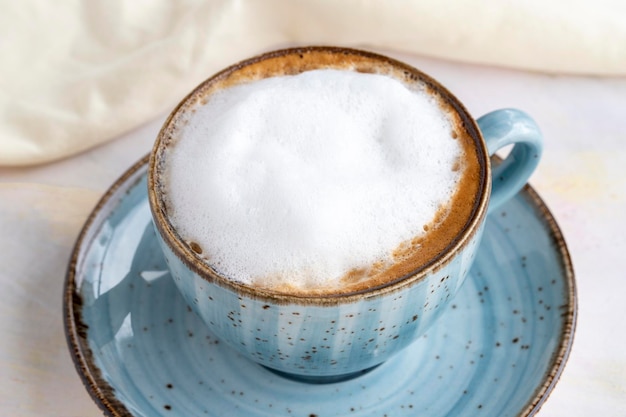 Cappuccino in schiuma su fondo di legno bianco