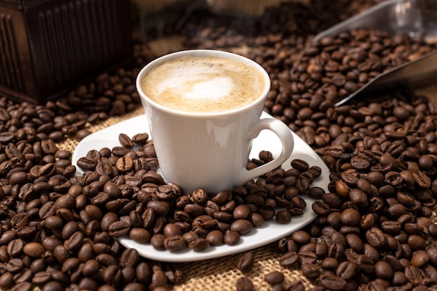 Cappuccino o caffè con tazza di latte e chicchi tostati sul tavolo