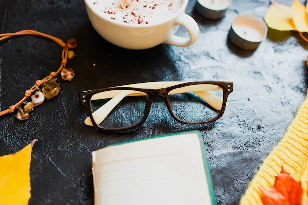 Cappuccino, occhiali e un maglione giallo brillante giacciono sul buio