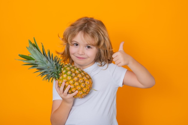 Capretto con ananas in studio Studio ritratto di bambino carino tenere ananas isolato su sfondo giallo