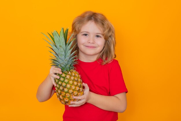 Capretto con ananas in studio Studio ritratto di bambino carino tenere ananas isolato su sfondo giallo