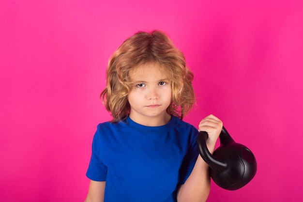Capretto con kettlebell in studio su sfondo rosa rosso Allenamento per bambini Sport per bambini Esercizio per bambini
