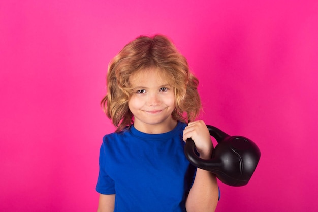 Capretto con kettlebell in studio su sfondo rosa rosso Attività sportive nel tempo libero con i bambini