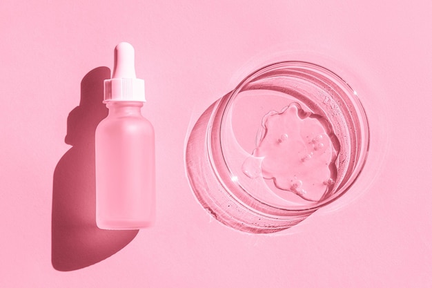 Capsula di Petri con gel trasparente Flacone cosmetico con pipetta Su sfondo rosa