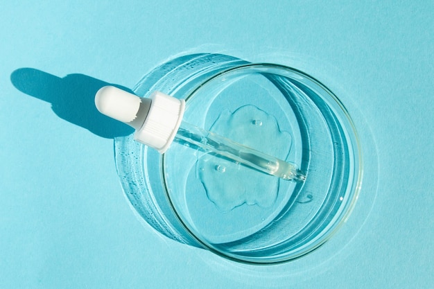 Capsula Petri Con gel trasparente La pipetta si trova Dispenser cosmetico Su sfondo blu