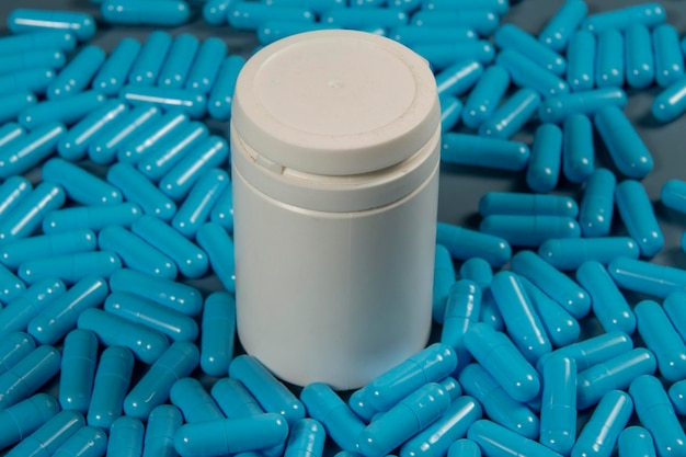 Capsule antibiotiche blu consistenti con bottiglia bianca Produzione farmaceutica Salute globale Resistenza agli antibiotici Capsule di gelatina