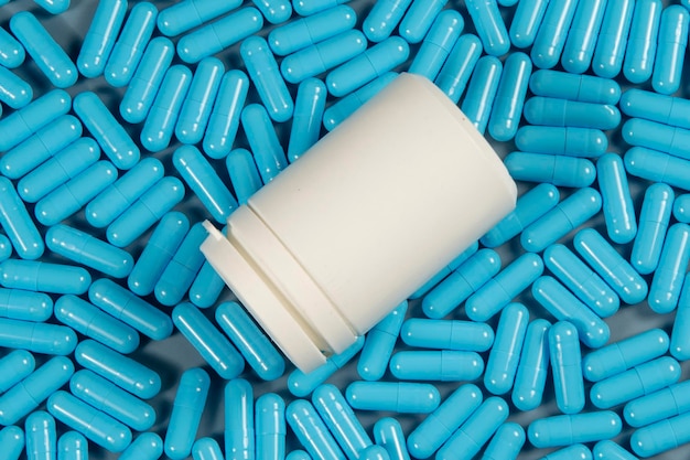 Capsule antibiotiche blu consistenti con bottiglia bianca Produzione farmaceutica Salute globale Resistenza agli antibiotici Capsule di gelatina