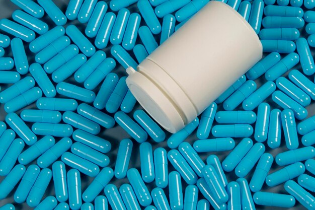 Capsule antibiotiche blu consistenti con bottiglia bianca Produzione farmaceutica Salute globale Resistenza agli antibiotici Capsule di gelatina