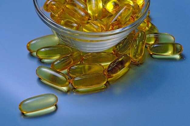 Capsule di olio di pesce Omega-3 e vitamina D in una lastra di vetro.