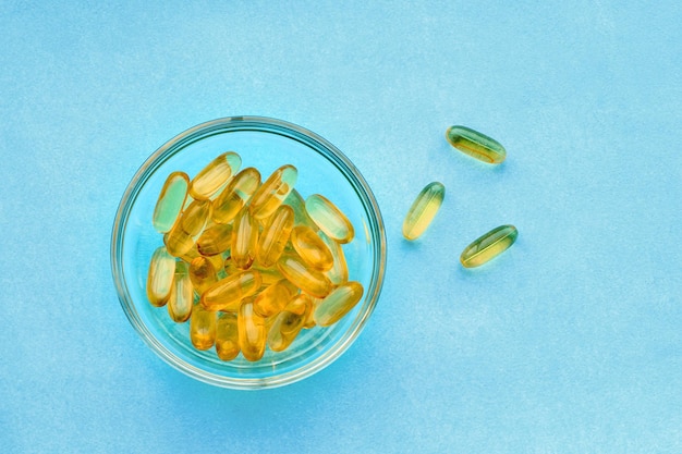 Capsule di olio di pesce su sfondo blu vitamine omega 3 e concetto di salute