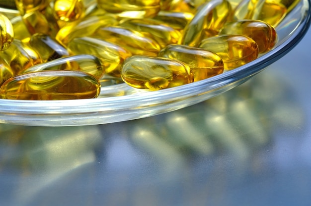 Capsule di olio di pesce su una lastra di vetro. Molta vitamina omega 3. Primo piano.