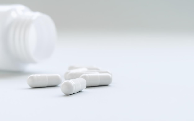 capsule di pillola bianca versate da un vaso bianco concetto di trattamento e medicina dei medicinali