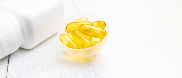 Capsule gialle Omega-3 in un misurino di plastica, integratori alimentari, vista ravvicinata.