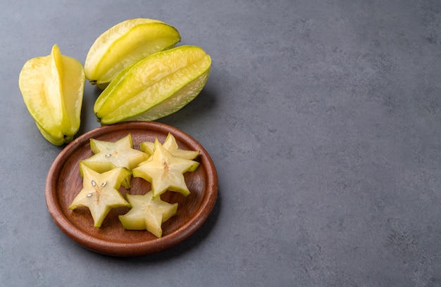 Carambola con fette in un piatto su sfondo di pietra con spazio per la copia