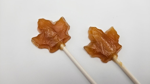 Caramelle a forma di foglia di acero realizzate con rivestimento di zucchero marrone su bastoncini bianchi esposti su un tavolo