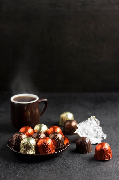 Caramelle al cioccolato avvolte in un foglio multicolore e una tazza di caffè