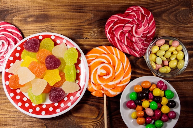 Caramelle al cioccolato colorate, lecca-lecca e caramelle gommose sul tavolo di legno