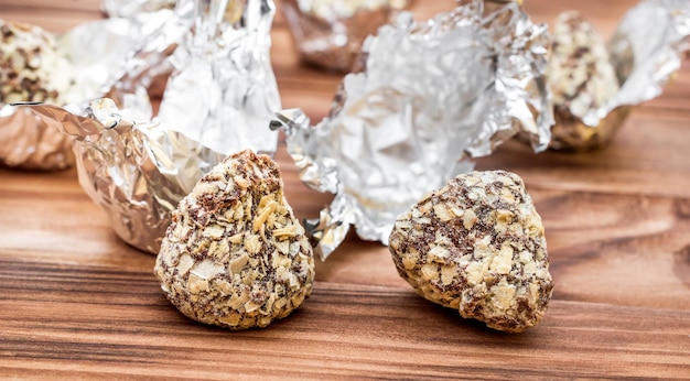 Caramelle al cioccolato con involucri in lamina d'argento su tavola di legno Primo piano