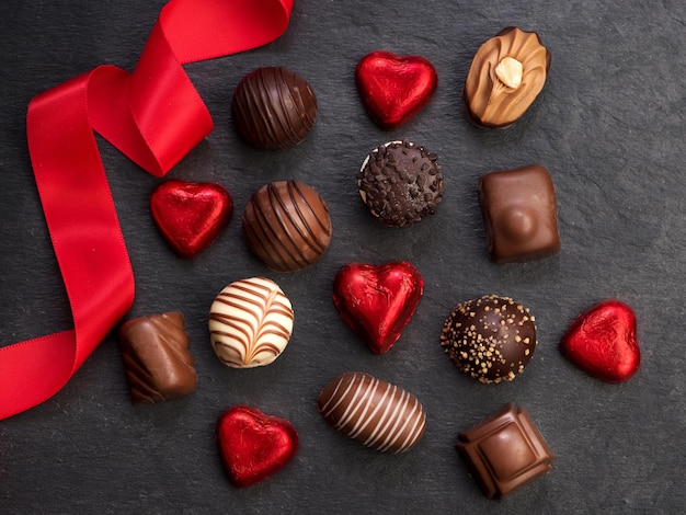 Caramelle al cioccolato con nastro rosso, vista dall'alto, distesi