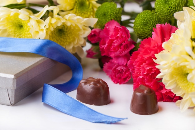 caramelle al cioccolato e fiori su bianco