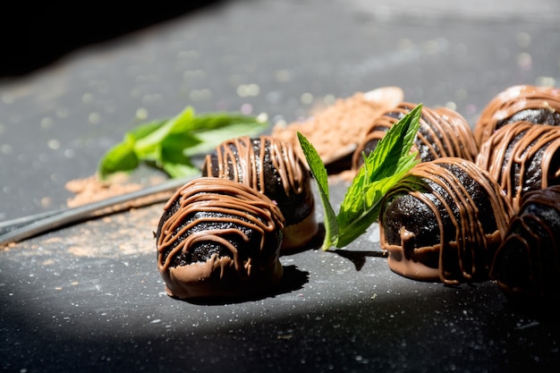 Caramelle al cioccolato fondente su fondo soleggiato tartufi al cioccolato con foglie di menta