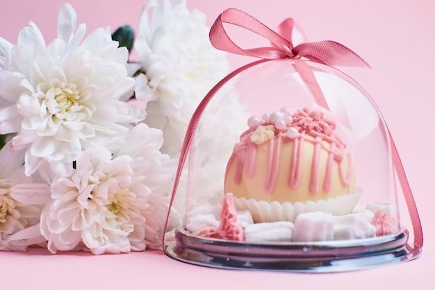 Caramelle al cioccolato in una confezione regalo su sfondo rosa con fiori