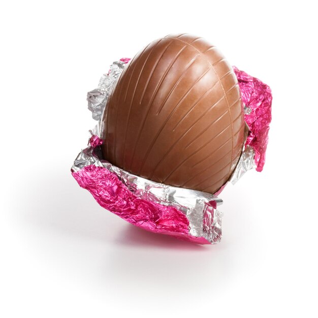 Caramelle al cioccolato Uovo di Pasqua avvolto in un foglio rosa su sfondo bianco percorso di ritaglio incluso