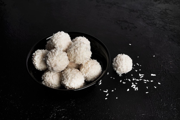 Caramelle al cocco con noci su sfondo scuro Raffaello su sfondo nero Foto di alta qualità